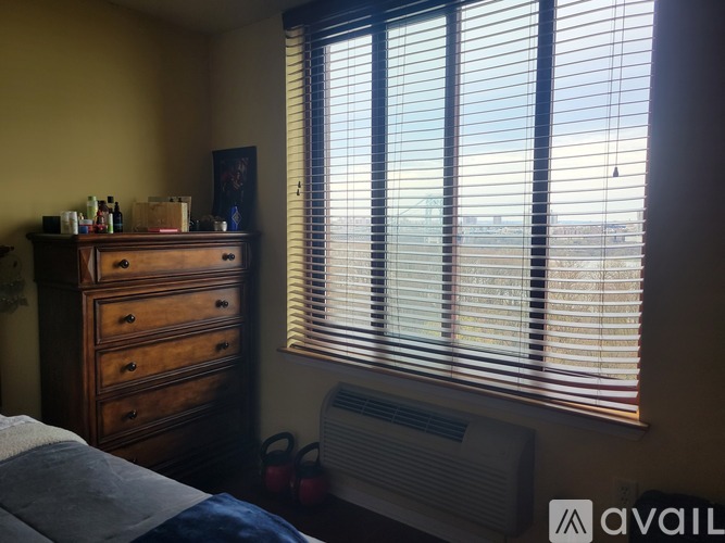 A bedroom with a bed, dresser, and window with blinds.