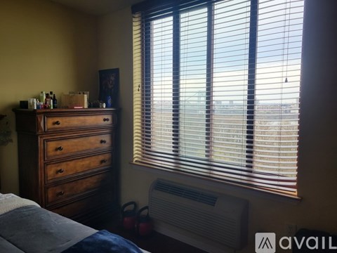 A bedroom with a bed, dresser, and window with blinds.