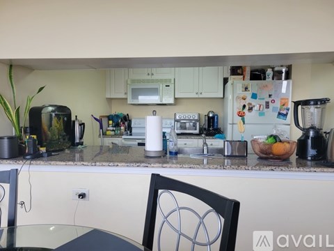A kitchen with a refrigerator covered in magnets, a microwave, a coffee maker, and a blender on the counter.