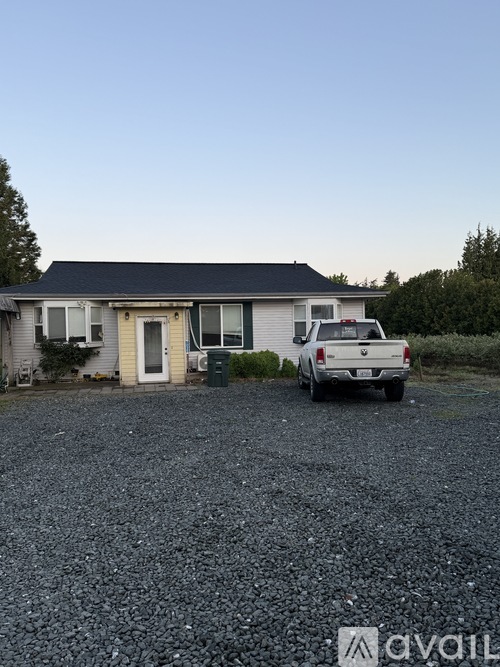 A house with a gravel driveway and a pickup truck parked in front.