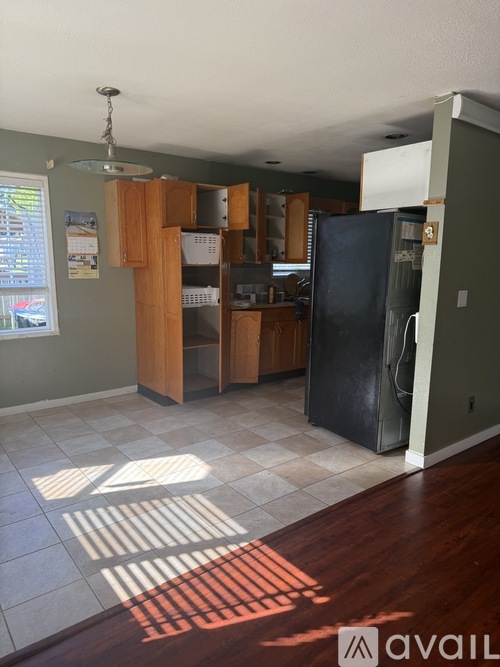 A kitchen with a black fridge and wooden cabinets.