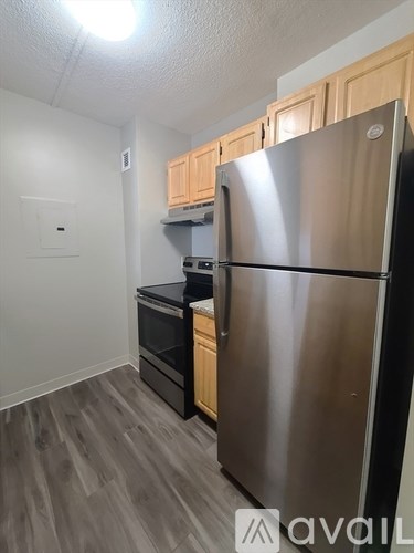 A kitchen with a stainless steel refrigerator and wooden cabinets.