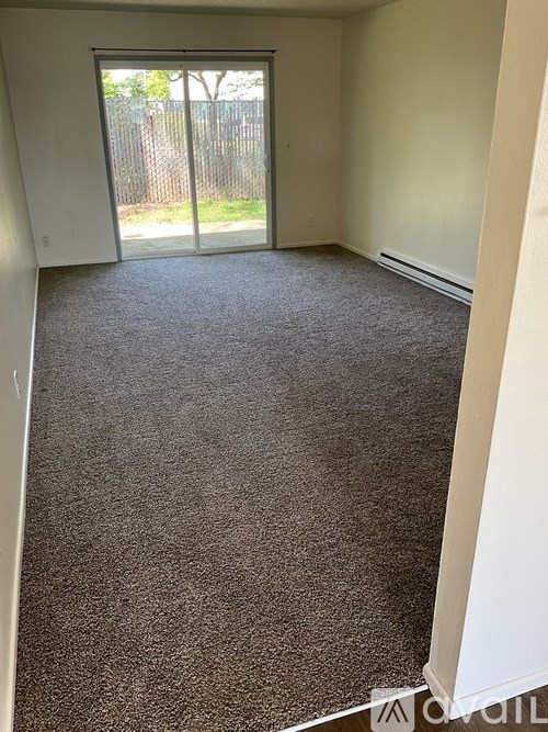 A carpeted room with a sliding glass door leading to a fenced area outside.