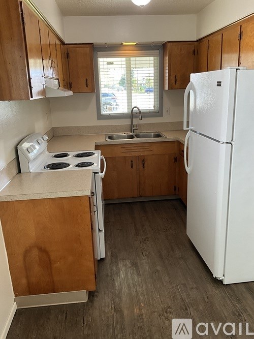 A kitchen with a white fridge, white stove, and wooden cabinets.