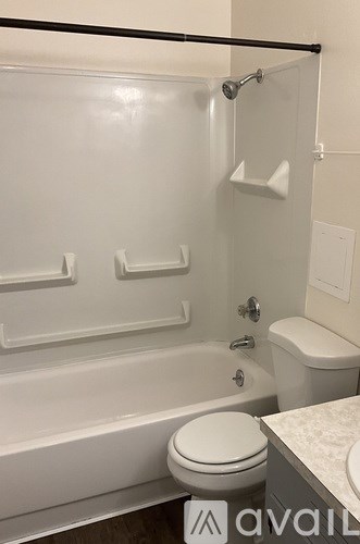 A white toilet sits in a bathroom next to a bathtub.