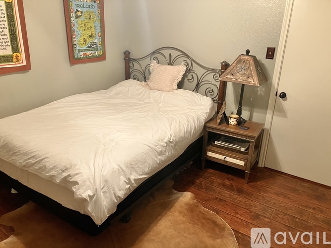A bedroom with a white bed and a lamp on a table.