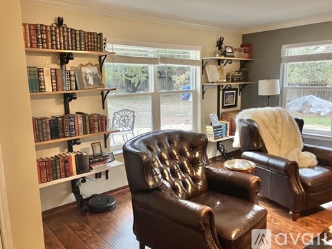 A living room with a brown leather chair and a bookshelf filled with books.