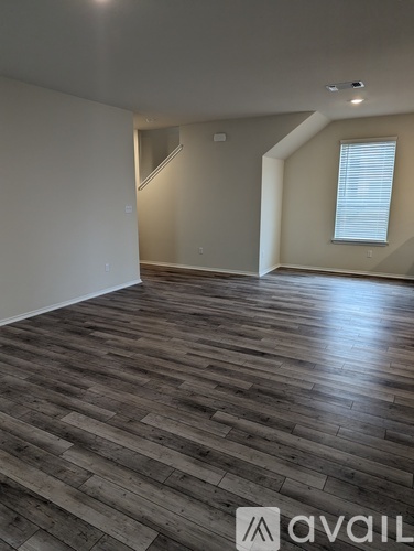 A room with wooden flooring and a window with blinds.