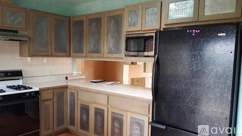 A kitchen with wooden cabinets and a black refrigerator.