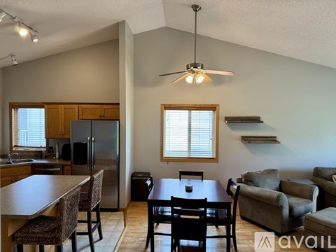 A kitchen with a refrigerator, a dining table with chairs, and a living room with a couch.