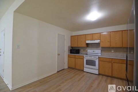 A kitchen with wooden cabinets and a white stove top oven.
