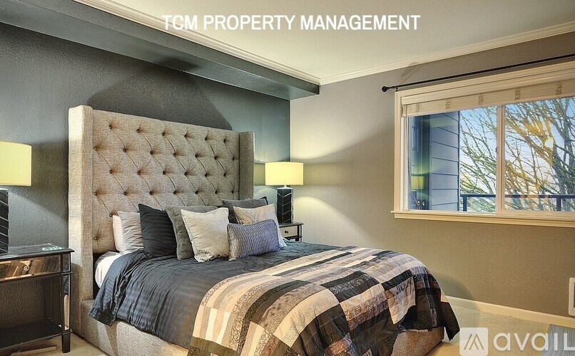 A bedroom with a large bed and a window showing trees outside.