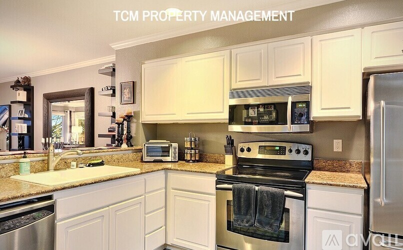 A kitchen with white cabinets and a stove top oven.