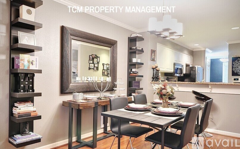 A dining room with a table set for four and a mirror above it.