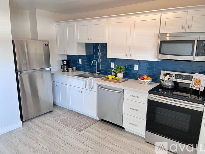 A kitchen with white cabinets and a blue tile backsplash.