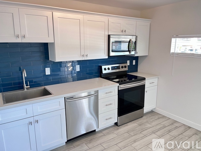 A kitchen with white cabinets and a blue backsplash.