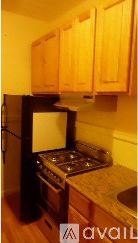 A kitchen with wooden cabinets and a black refrigerator.