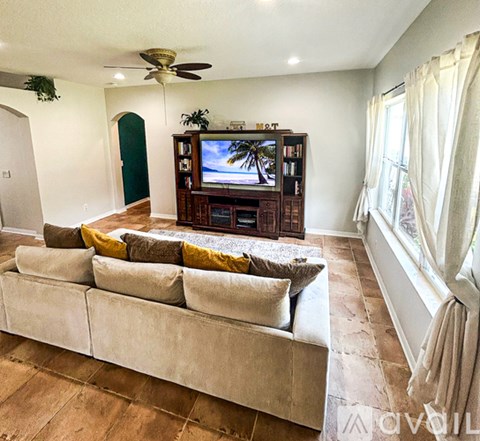 A living room with a large couch and a television on a wooden stand.