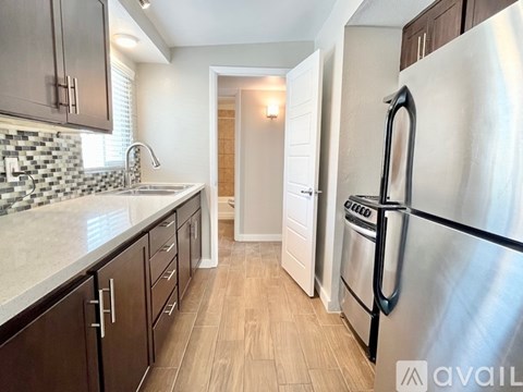 A kitchen with a stainless steel refrigerator and wooden floors.