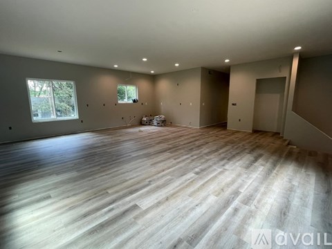 A spacious room with wooden flooring and a window.