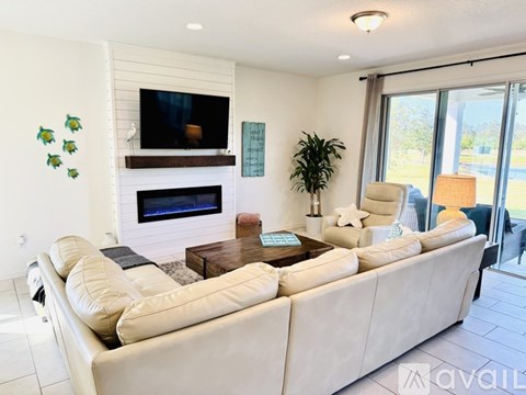 A living room with a white couch and a flat screen TV mounted above a fireplace.