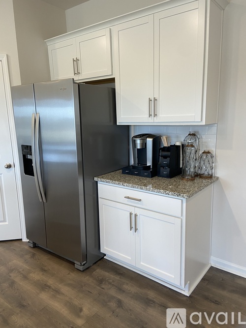 A kitchen with a stainless steel refrigerator and white cabinets.