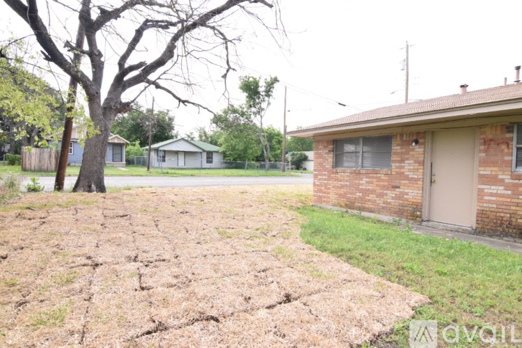 A cracked dry ground with a tree and a house in the background.
