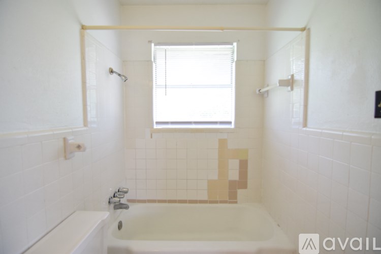 A white bathroom with a tub and a window.