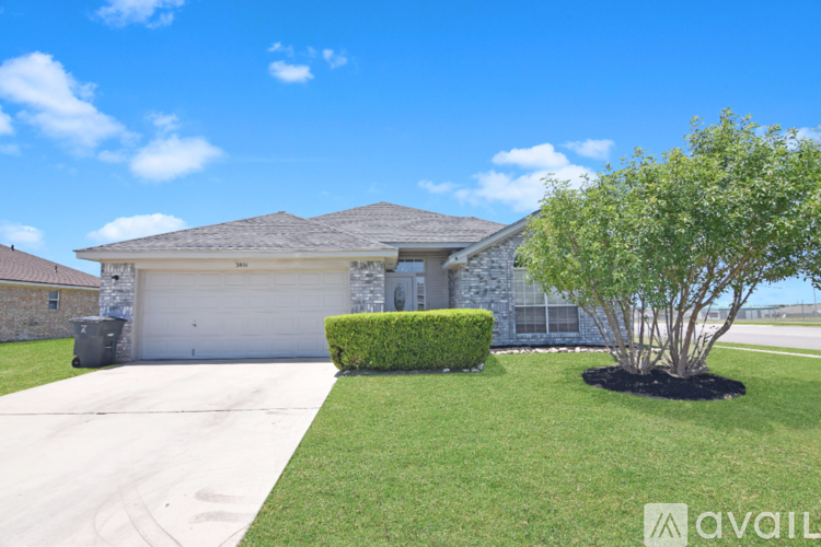 A house with a driveway and a tree in front.