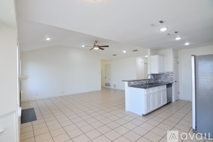 A spacious kitchen and living room with white cabinets and a black countertop.