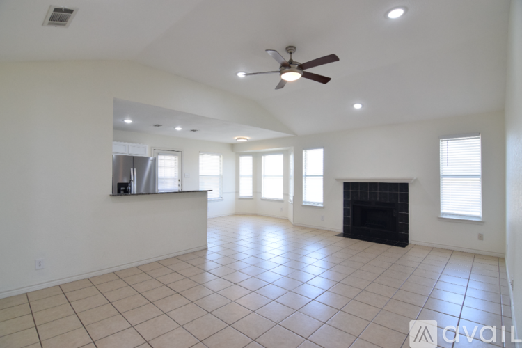 A spacious living room with a fireplace and a ceiling fan.