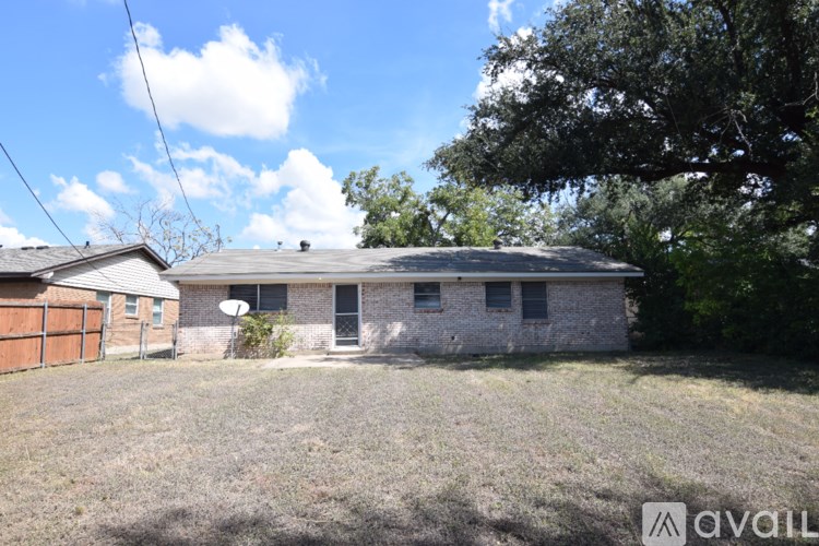 A house with a satellite dish on the roof is surrounded by grass and trees.