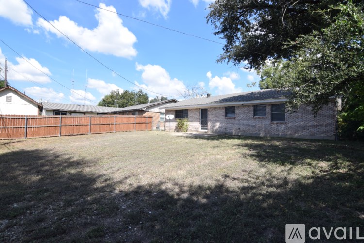 A backyard with a fence and a house in the background.