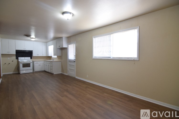 A spacious living room with a kitchen area in the background.