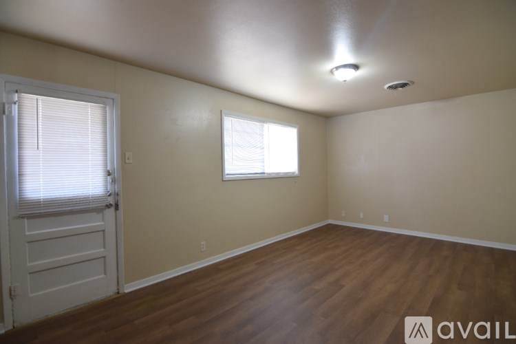 A room with wooden floors and a window with blinds.
