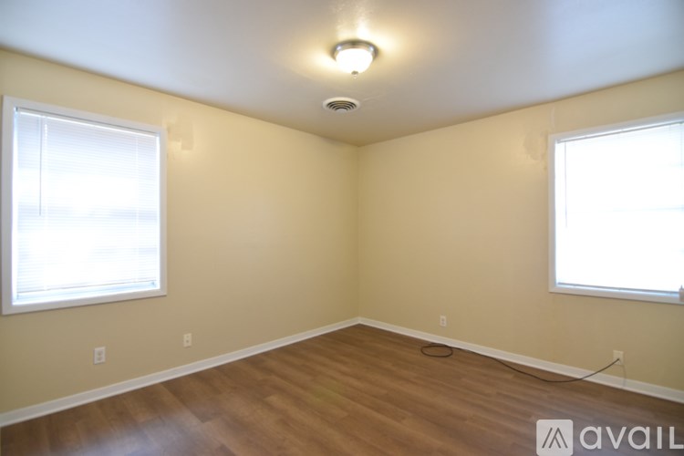 A room with wooden floors and two windows.