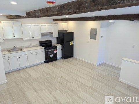 A kitchen with white cabinets and a black fridge.