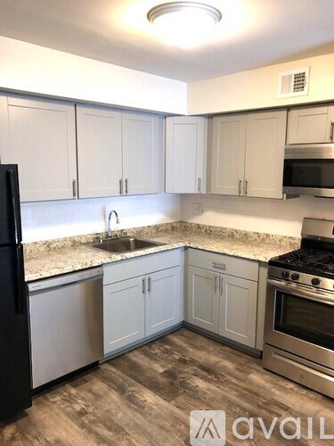 A kitchen with white cabinets and a black refrigerator.