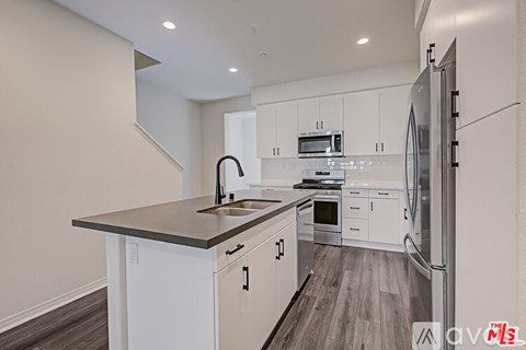 A modern kitchen with white cabinets and a dark countertop.