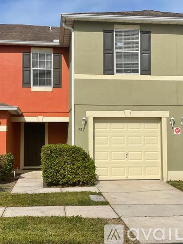 A two-story house with a garage and a small bush in front.