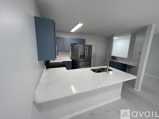 A kitchen with a marble countertop and a refrigerator.