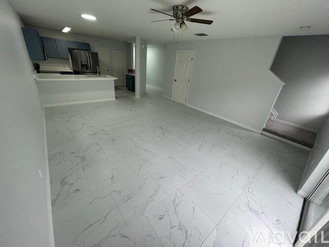 A room with a ceiling fan and marble flooring.