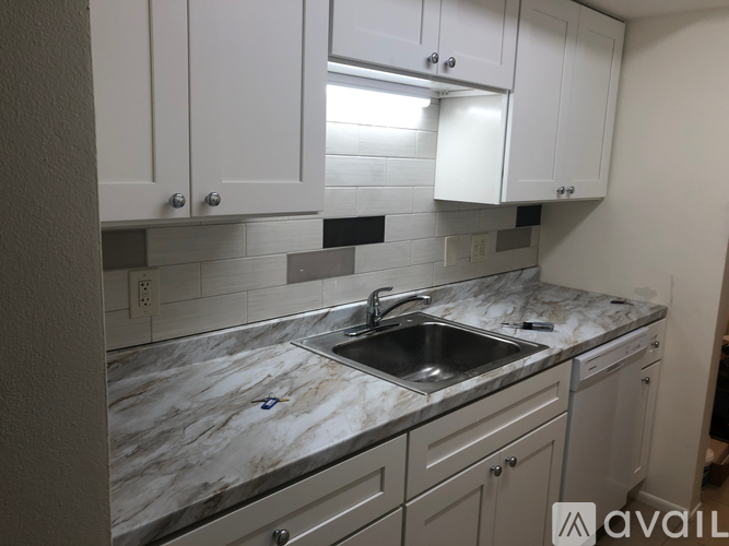 A kitchen with a marble countertop and white cabinets.