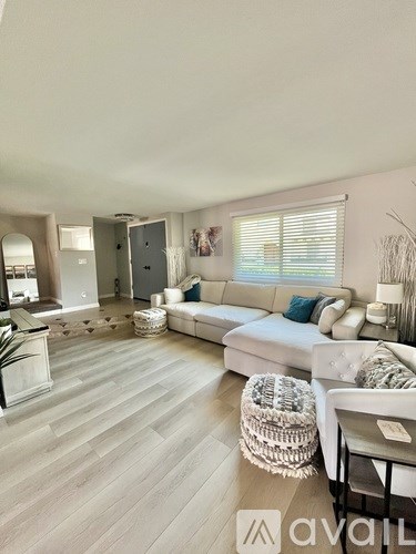 A living room with a white couch and a wooden floor.