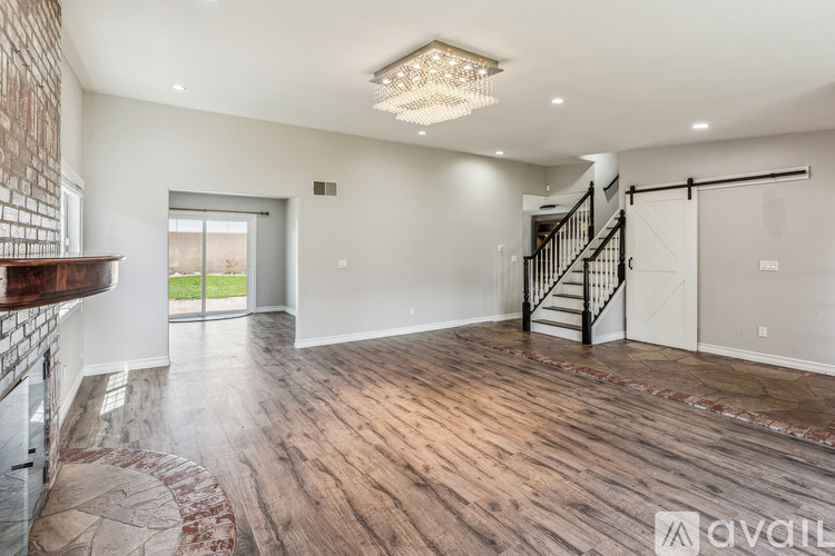 A spacious room with wooden floors and a staircase.