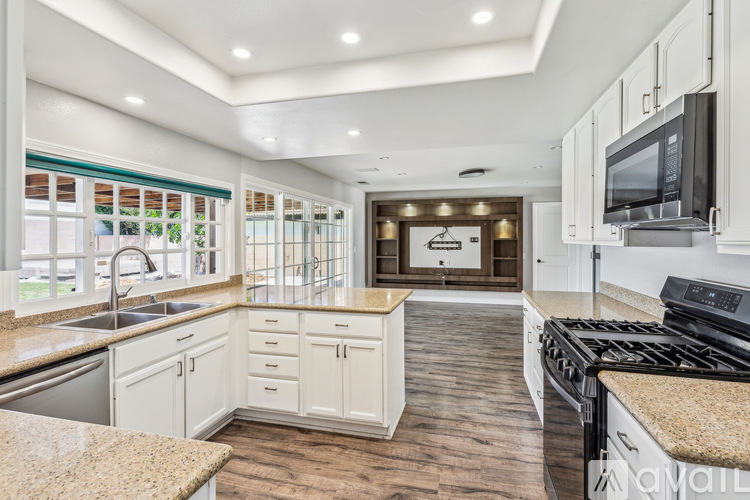 A modern kitchen with white cabinets and a granite countertop.