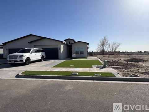 A white car is parked in front of a house with a garage.
