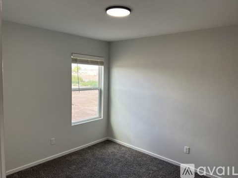 A room with a window and a carpeted floor.