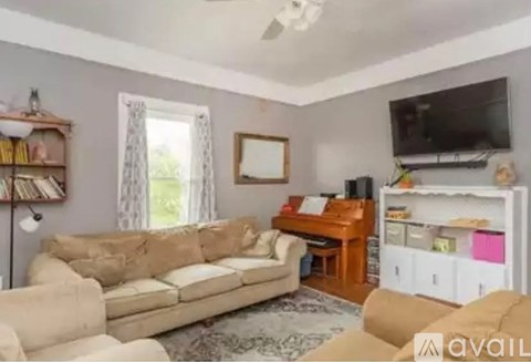 A living room with a beige sofa and a television on the wall.