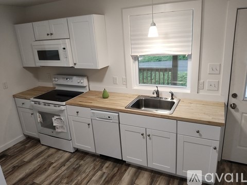 A kitchen with white cabinets and a wooden countertop.